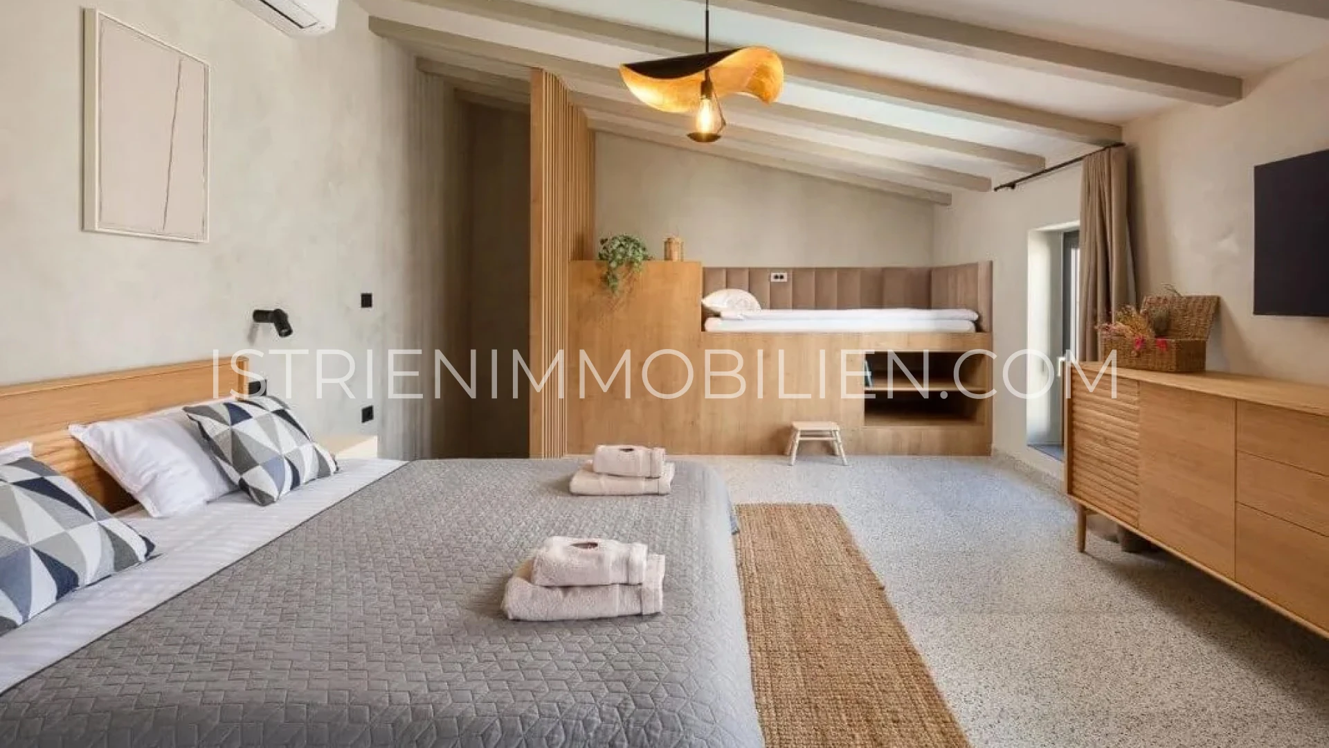 Großzügiges Schlafzimmer mit Holzeinbauten, Doppelbett und sichtbaren Deckenbalken