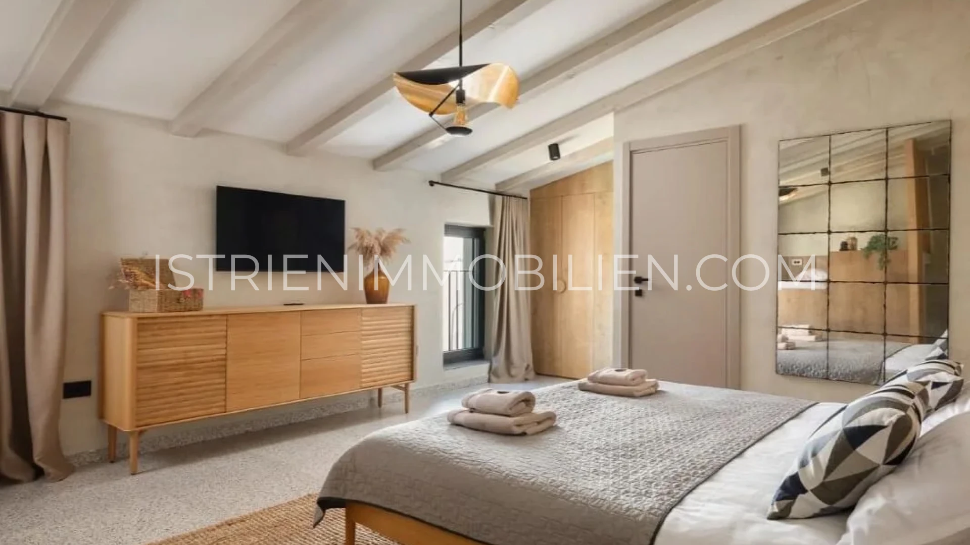 Stilvolles Schlafzimmer mit Doppelbett, Holzkommode und großem Wandspiegel