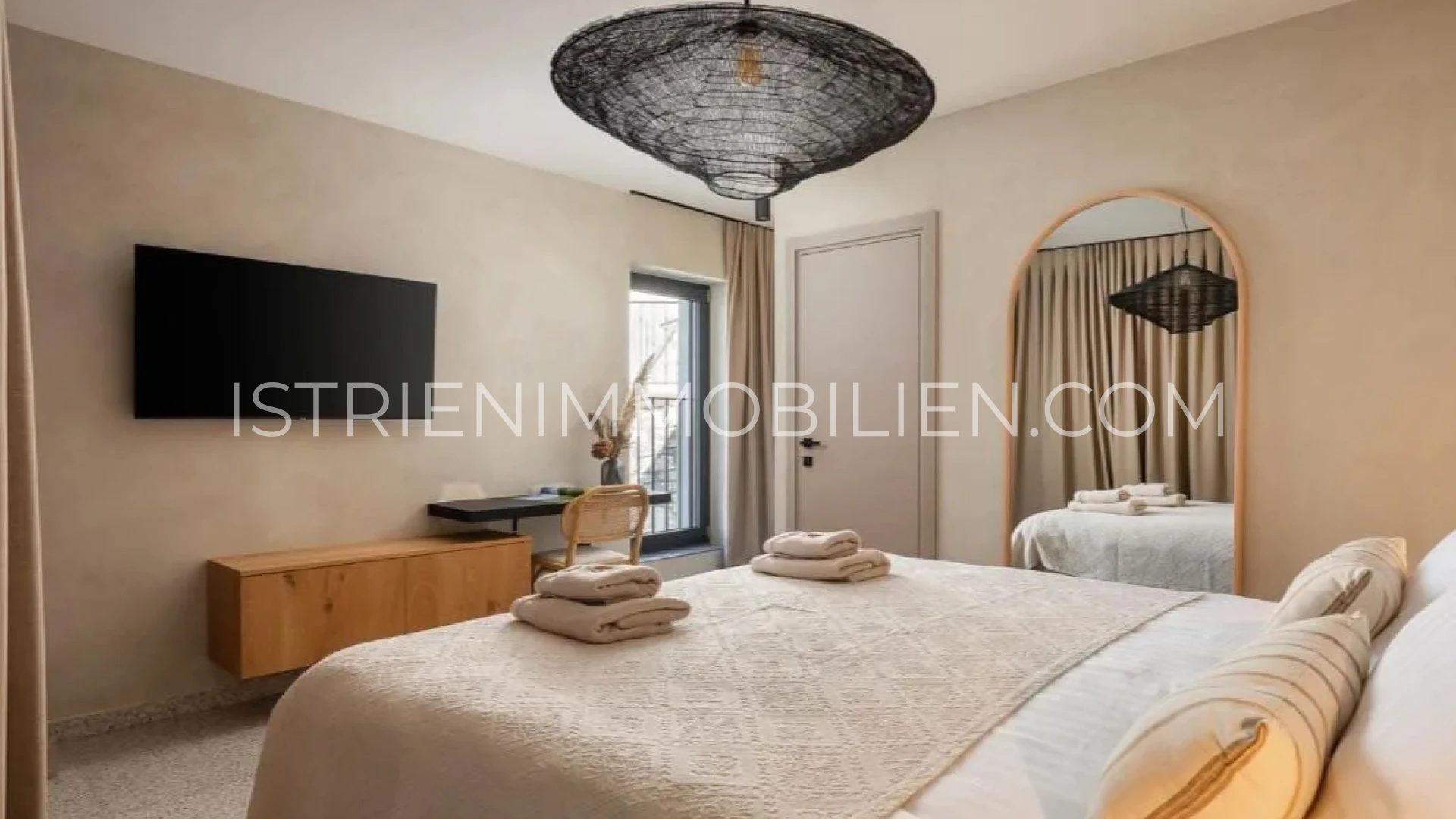 Elegantes Schlafzimmer mit großem Bett, Schreibtisch und warmen Naturtönen